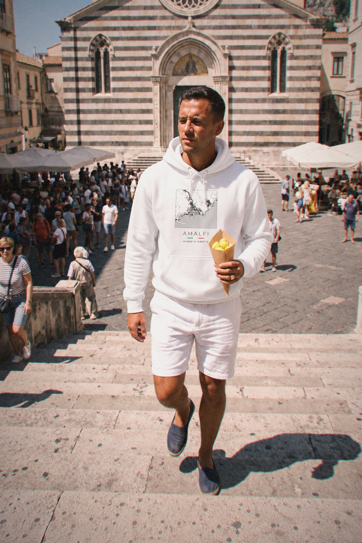 A man wearing the white hoodie carrying the real street map of Amalfi as a square, photographed in Amalfi