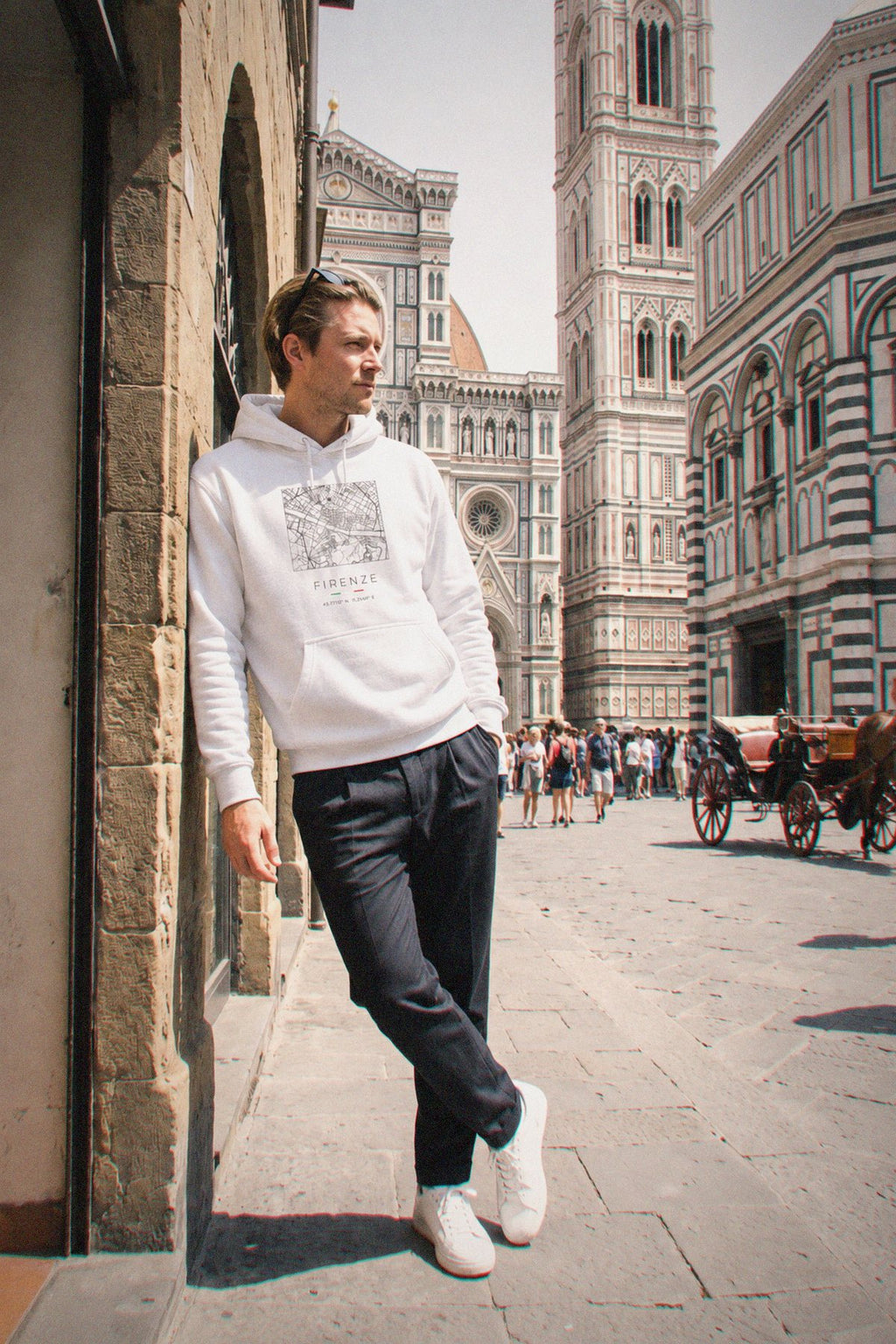 A man wearing the white hoodie carrying the real street map of Florence as a square, photographed in Florence