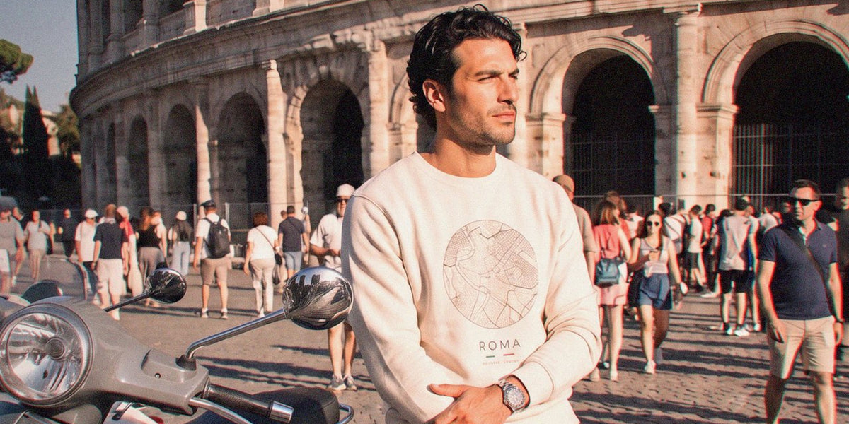 Man in the Sand Rome street map sweatshirt beside a Vespa in front of the Colosseum