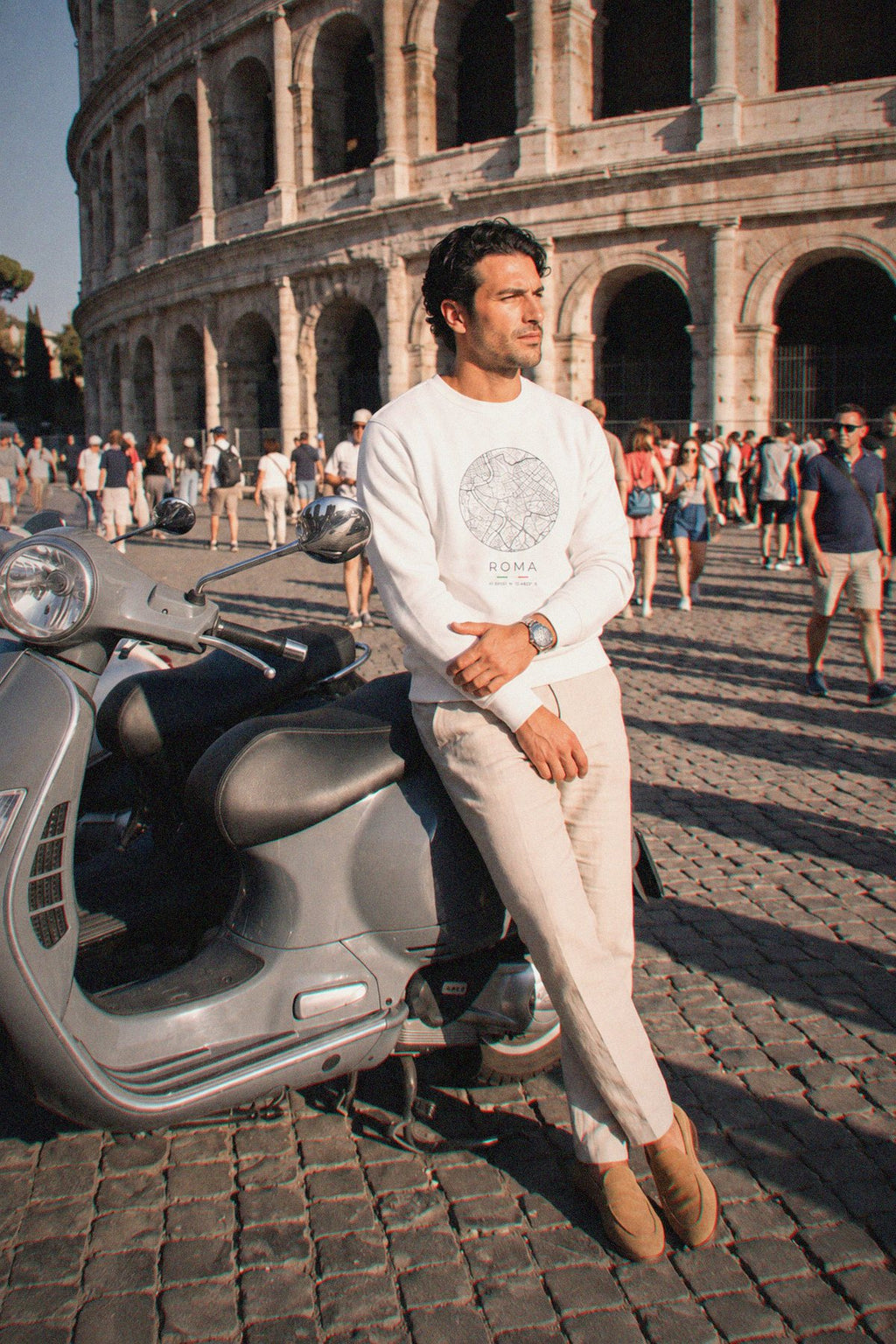 A man wearing the white crewneck sweatshirt carrying the real street map of Rome as a circle, photographed in Rome