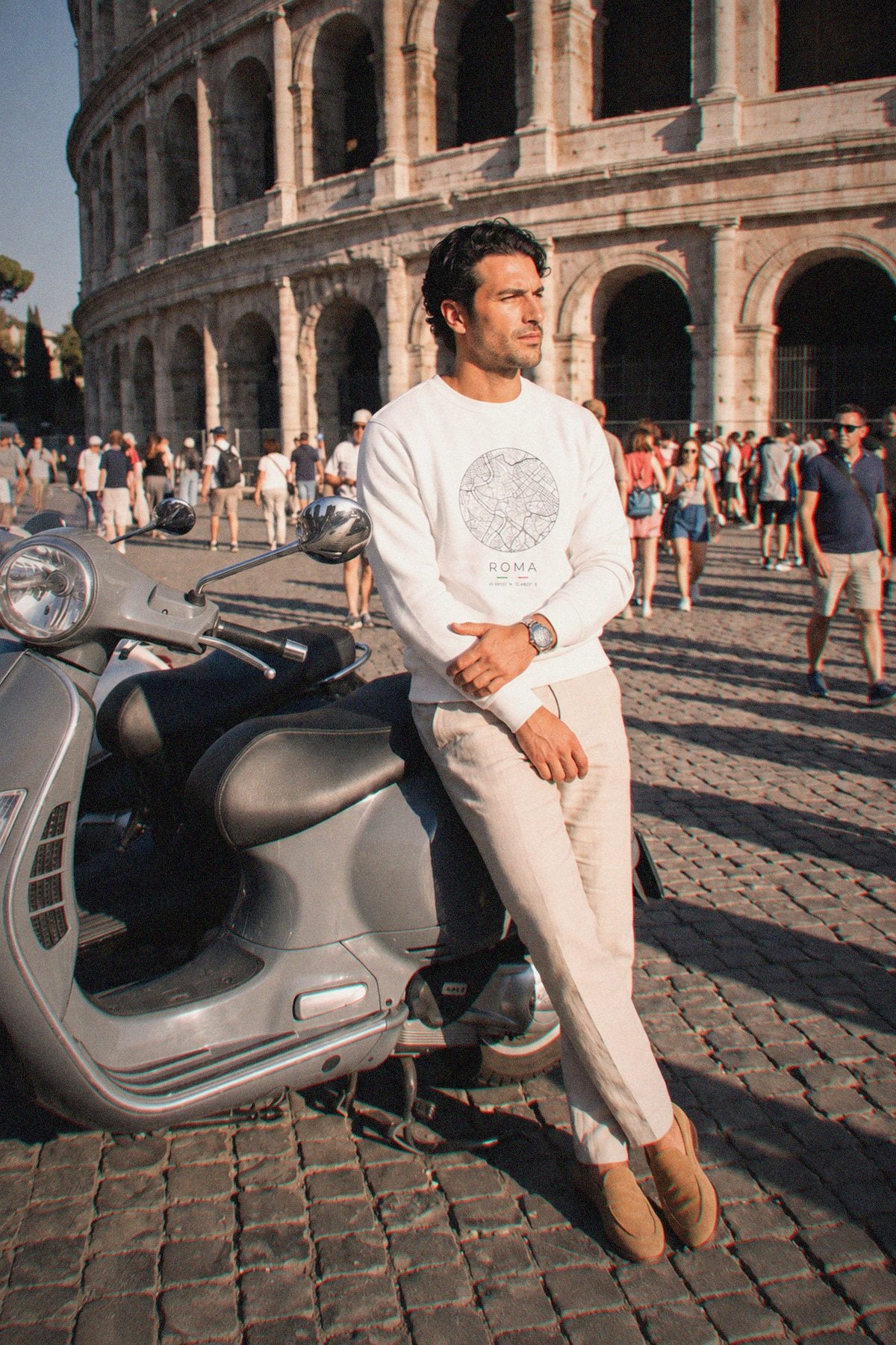 A man wearing the white crewneck sweatshirt carrying the real street map of Rome as a circle, photographed in Rome