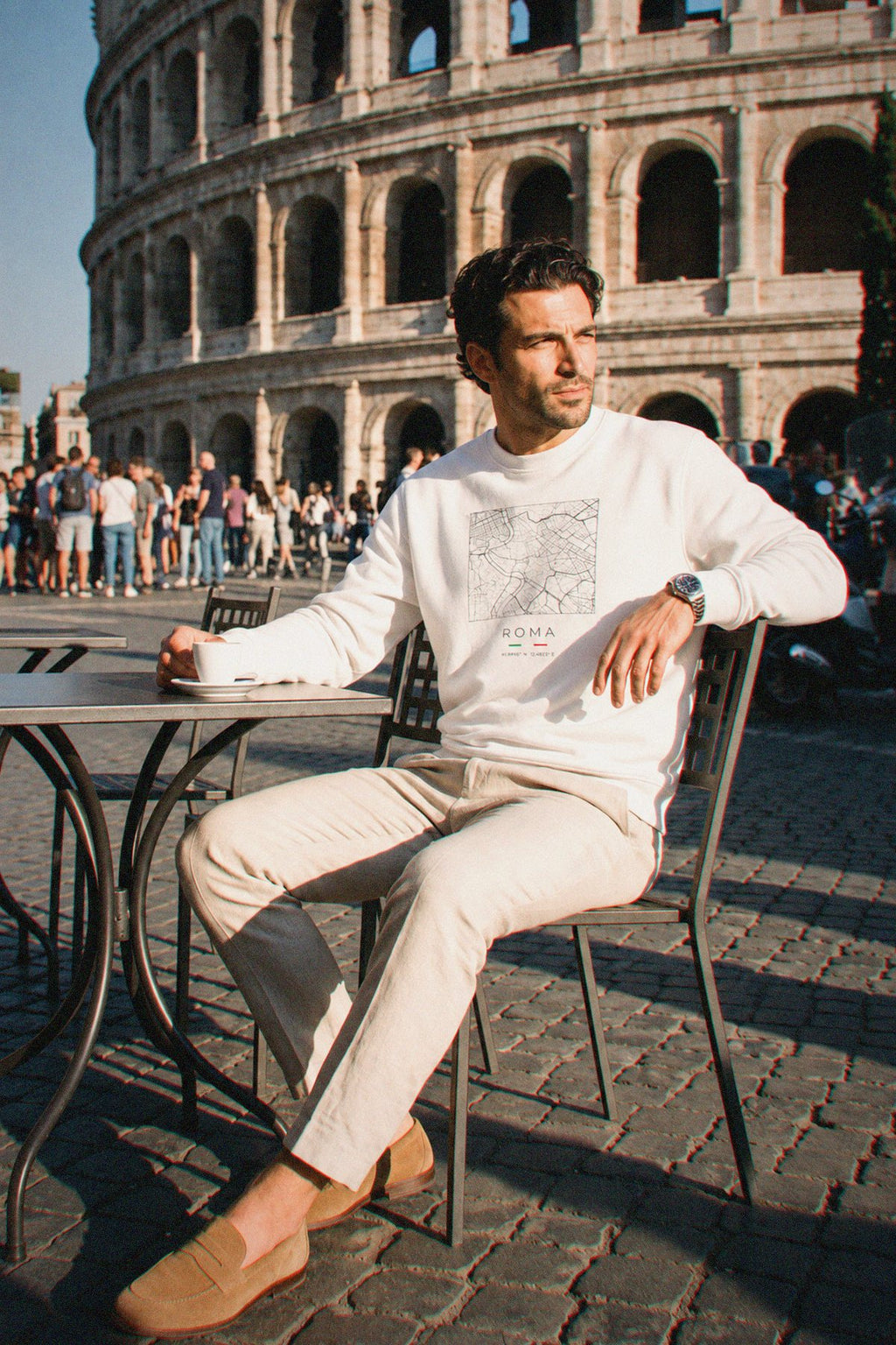 A man wearing the white crewneck sweatshirt carrying the real street map of Rome as a square, photographed in Rome