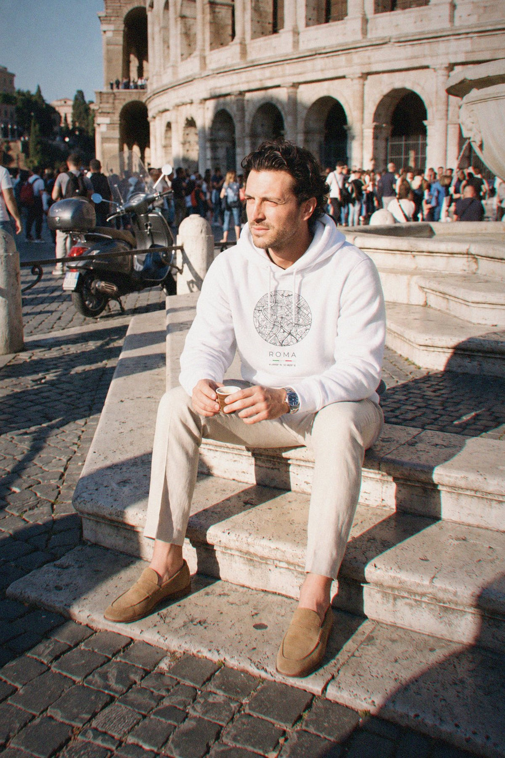 A man wearing the white hoodie carrying the real street map of Rome as a circle, photographed in Rome