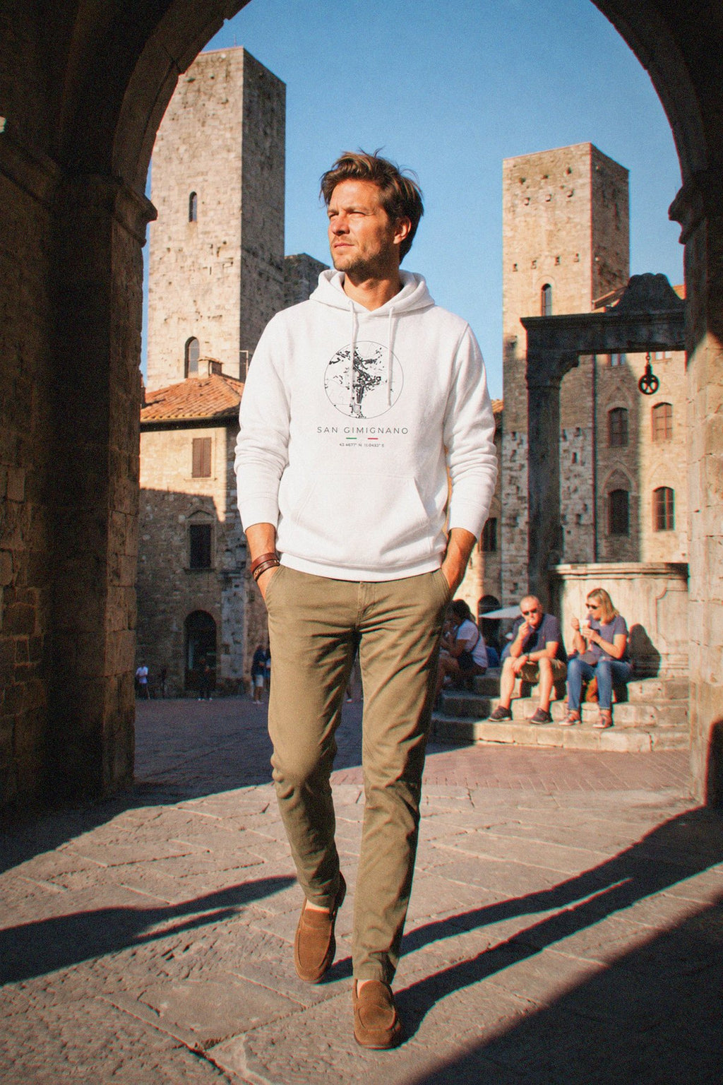 A man wearing the white hoodie carrying the real street map of San Gimignano as a circle, photographed in San Gimignano