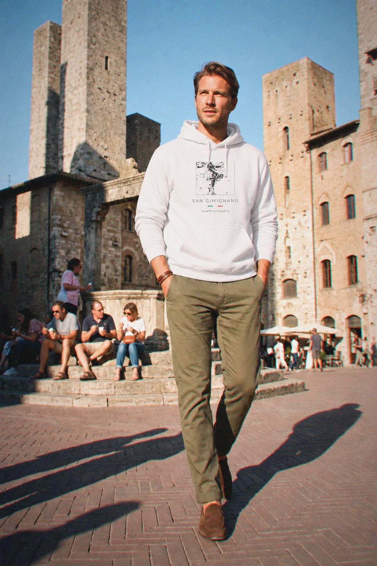 A man wearing the white hoodie carrying the real street map of San Gimignano as a square, photographed in San Gimignano