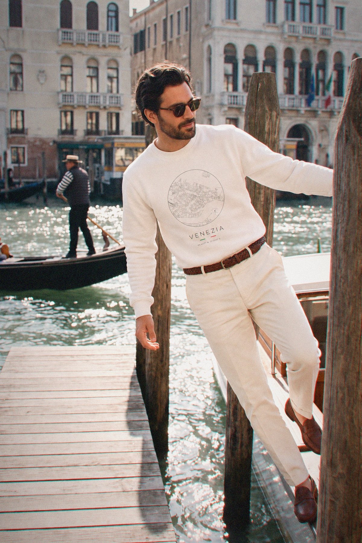 A man wearing the white crewneck sweatshirt carrying the real street map of Venice as a circle, photographed in Venice