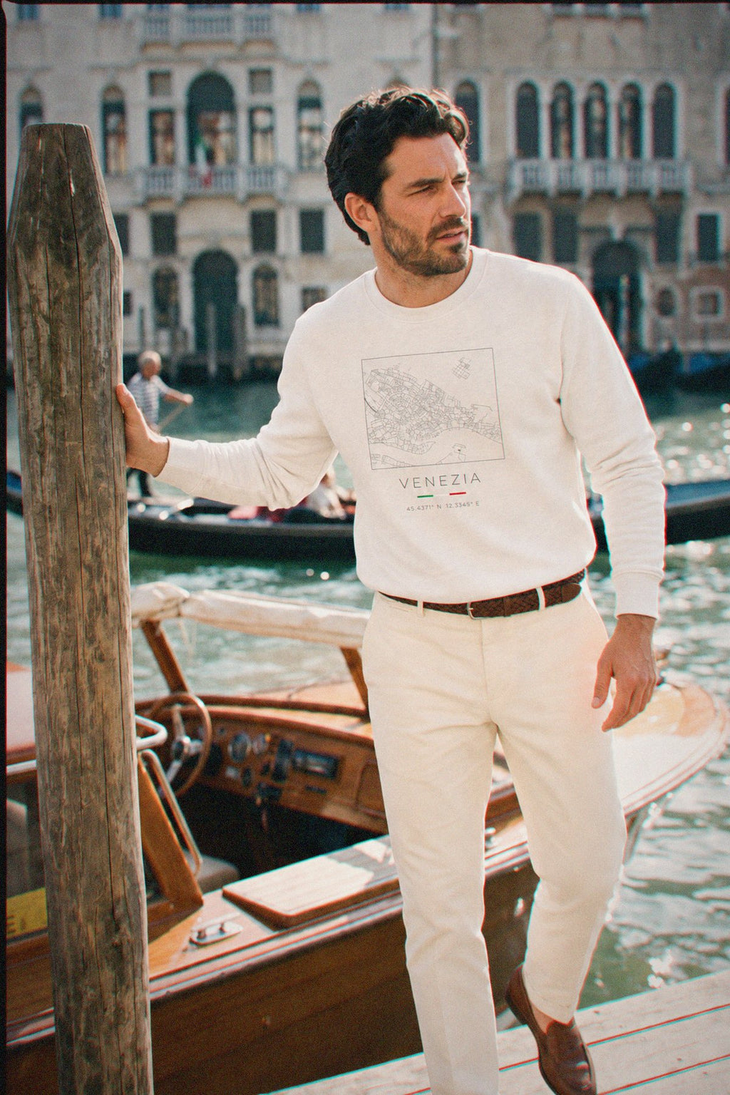 A man wearing the white crewneck sweatshirt carrying the real street map of Venice as a square, photographed in Venice
