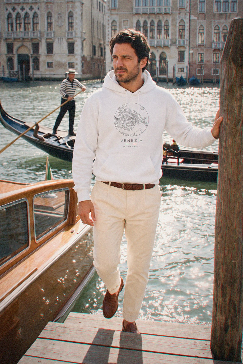 A man wearing the white hoodie carrying the real street map of Venice as a circle, photographed in Venice