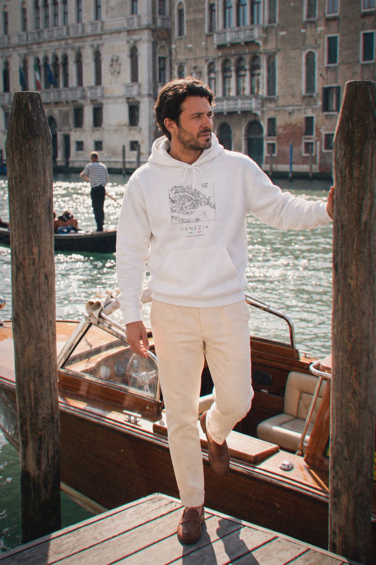 A man wearing the white hoodie carrying the real street map of Venice as a square, photographed in Venice